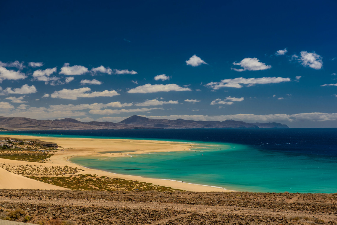 Panoramic view of Playa de Sotavento in southern Fuerteventura, where wide golden sands meet shallow turquoise lagoons and the Atlantic Ocean.