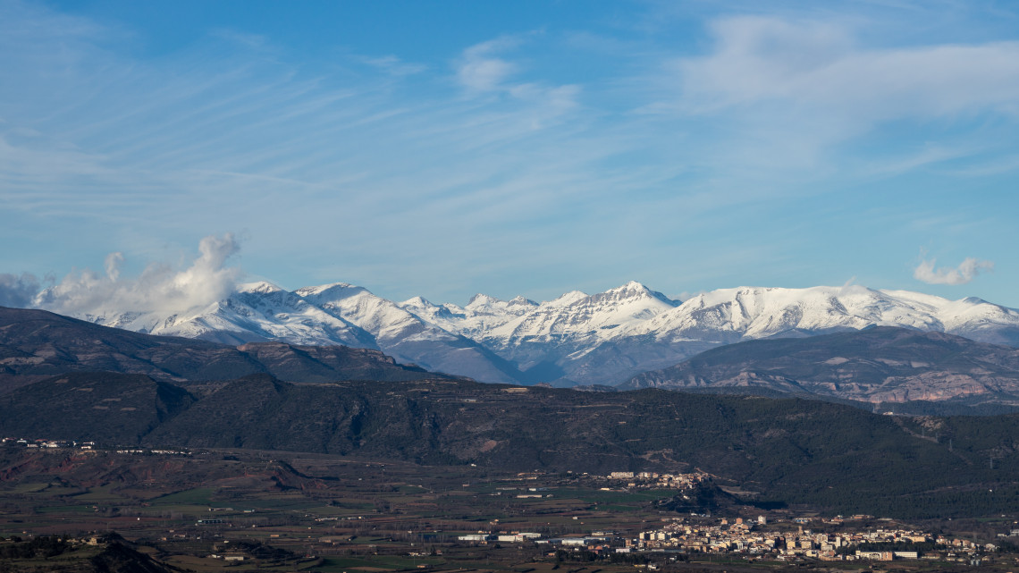Snow-covered Pyrenees mountain range with a small Spanish town in the valley below