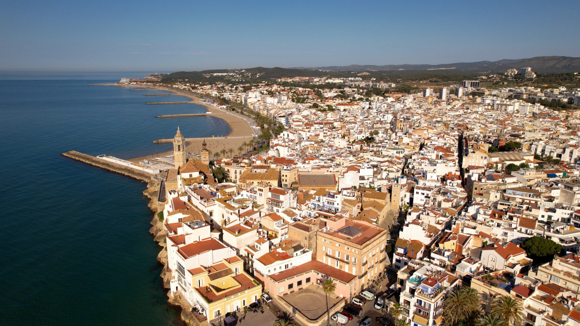 Aerial view of Sitges, a whitewashed coastal town on Spain's Catalan coast, with a church on the rocky point