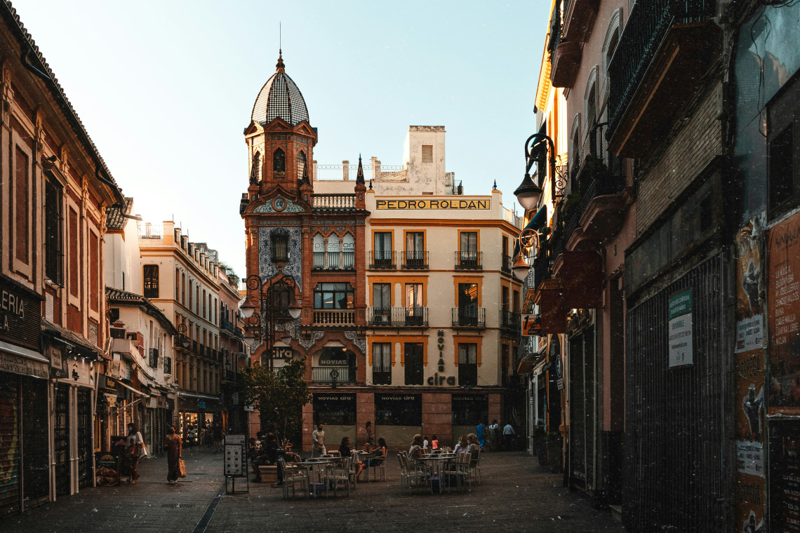The Pedro Rold&aacute;n Building overlooks Plaza del Pan in the historic centre of Seville, Spain. Its decorative corner tower, patterned brickwork and tiled dome rise above an outdoor caf&eacute; and surrounding streets