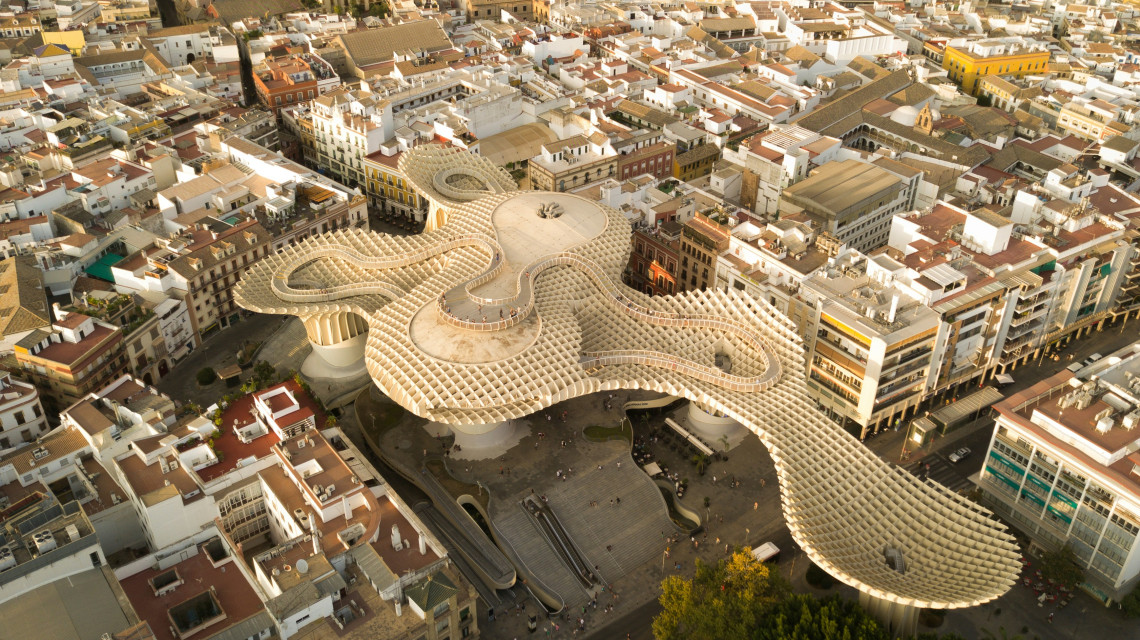 Aerial view of the Metropol Parasol in Seville, Spain, showing its interconnected wooden canopy above Plaza de la Encarnaci&oacute;n. Dense rooftops and streets surround the contemporary landmark.