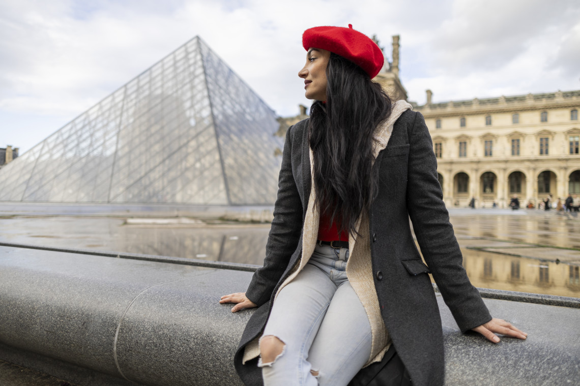 Young woman wearing a beret posing in front of a Parisian landmark in France