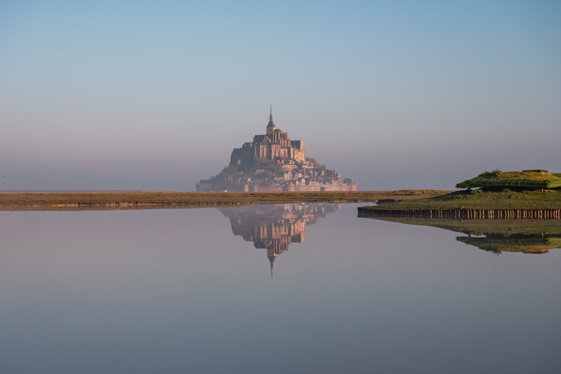 Mont Saint-Michel abbey rising on a tidal island at sunset in Normandy, France