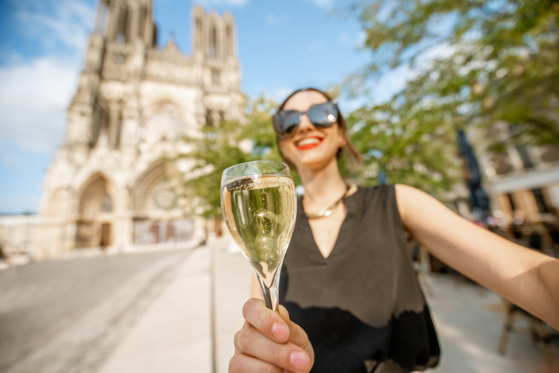 Woman holding a glass of champagne during a cellar tour in Reims, Champagne region, France
