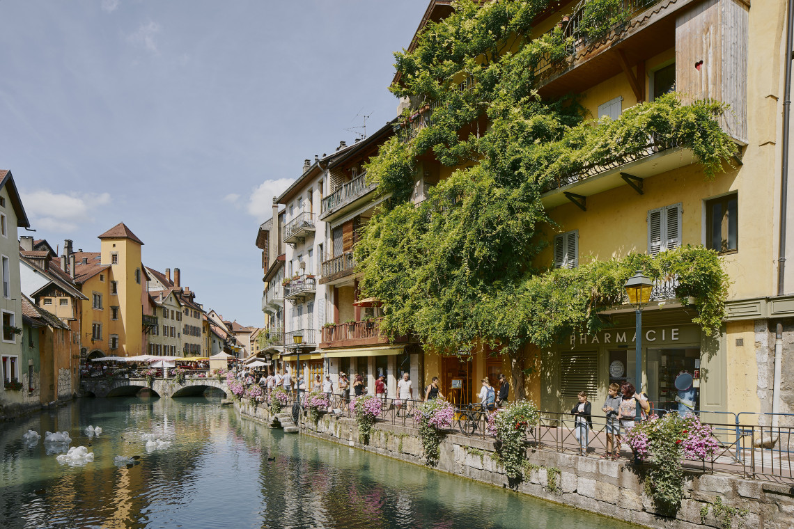 Colorful canalside buildings and flower-lined bridges in the old town of Annecy, French Alps, France