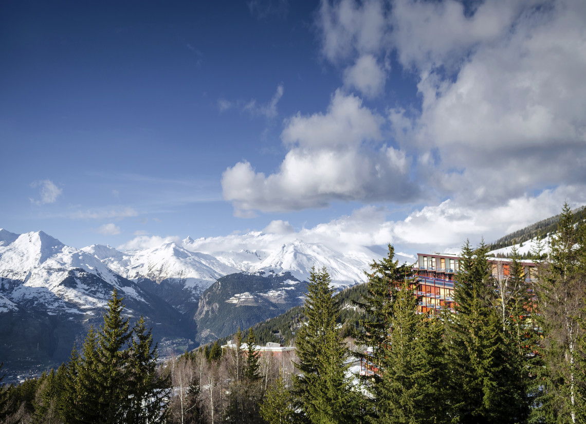Snow-covered French Alps peaks with pine trees and a mountain chalet at Les Arcs ski resort, France
