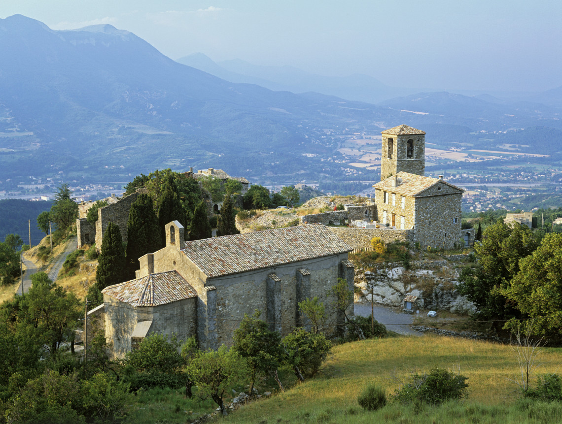 Historic stone village with church tower perched on a hilltop with mountain valley views in Corsica, France