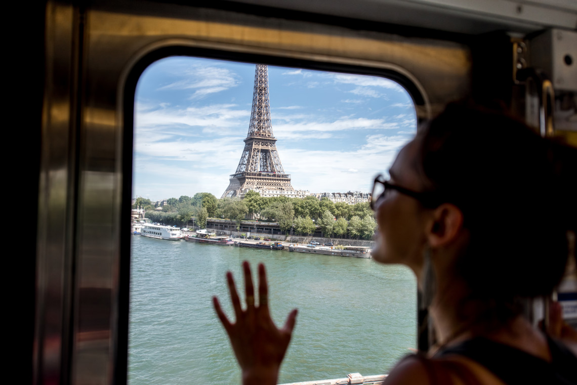 Woman looking at the Eiffel Tower and Seine River through a train window in Paris, France
