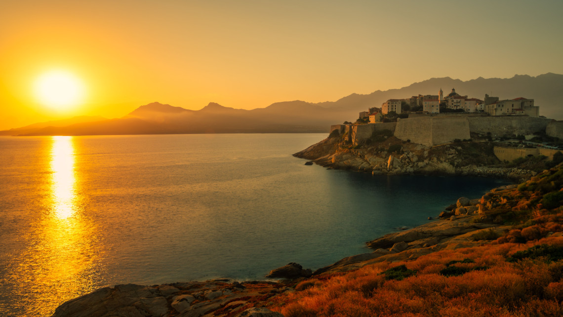  Golden sunset over the Genoese citadel of Calvi perched on a rocky headland above the Mediterranean Sea, Corsica, France
