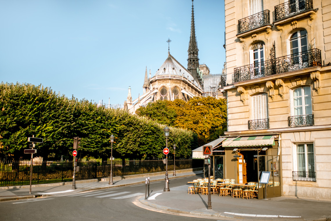  Quiet Paris street corner with a cafe terrace and the apse of Notre-Dame Cathedral visible through the trees, Ile de la Cite, Paris, France