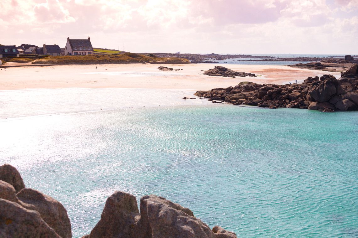 White sand beach with turquoise water and pink granite boulders along the Pink Granite Coast in Brittany France