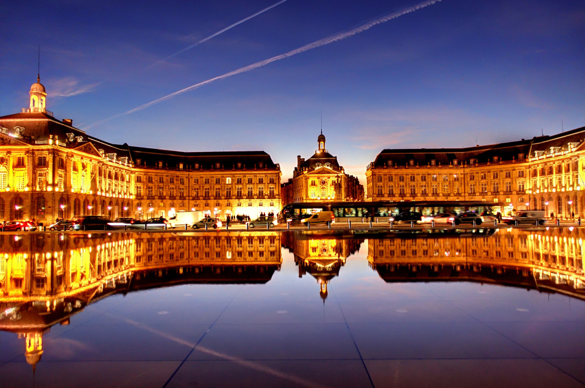  Illuminated Place de la Bourse reflected in the Miroir d'Eau water mirror at night in Bordeaux, France