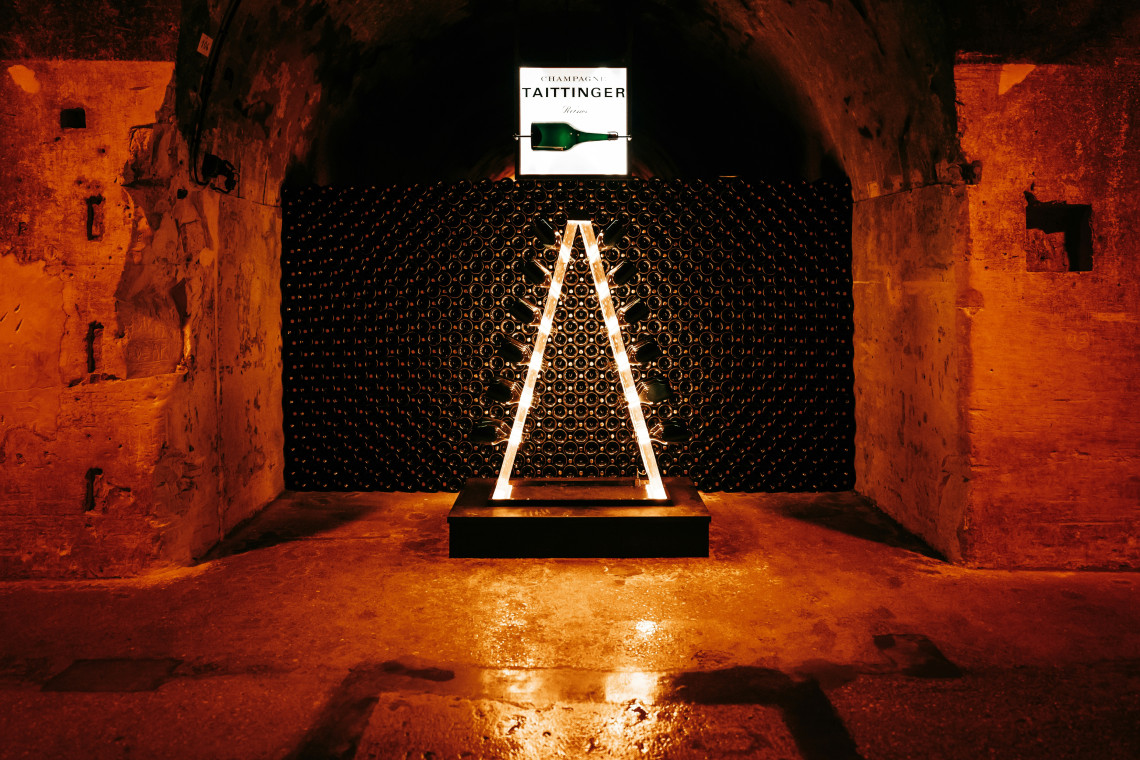  Illuminated Taittinger champagne bottles stacked in the historic chalk cellars of the Taittinger house in Reims, Champagne, France