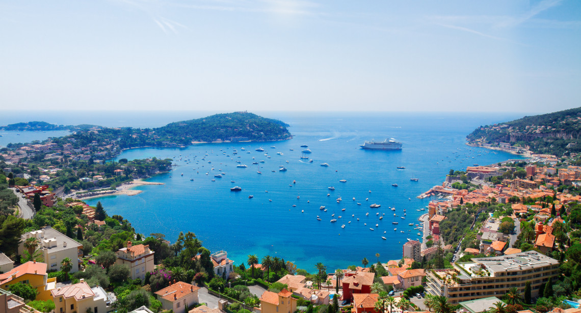 Panoramic aerial view of Villefranche-sur-Mer bay with sailboats, cruise ship and Cap Ferrat peninsula on the French Riviera, France