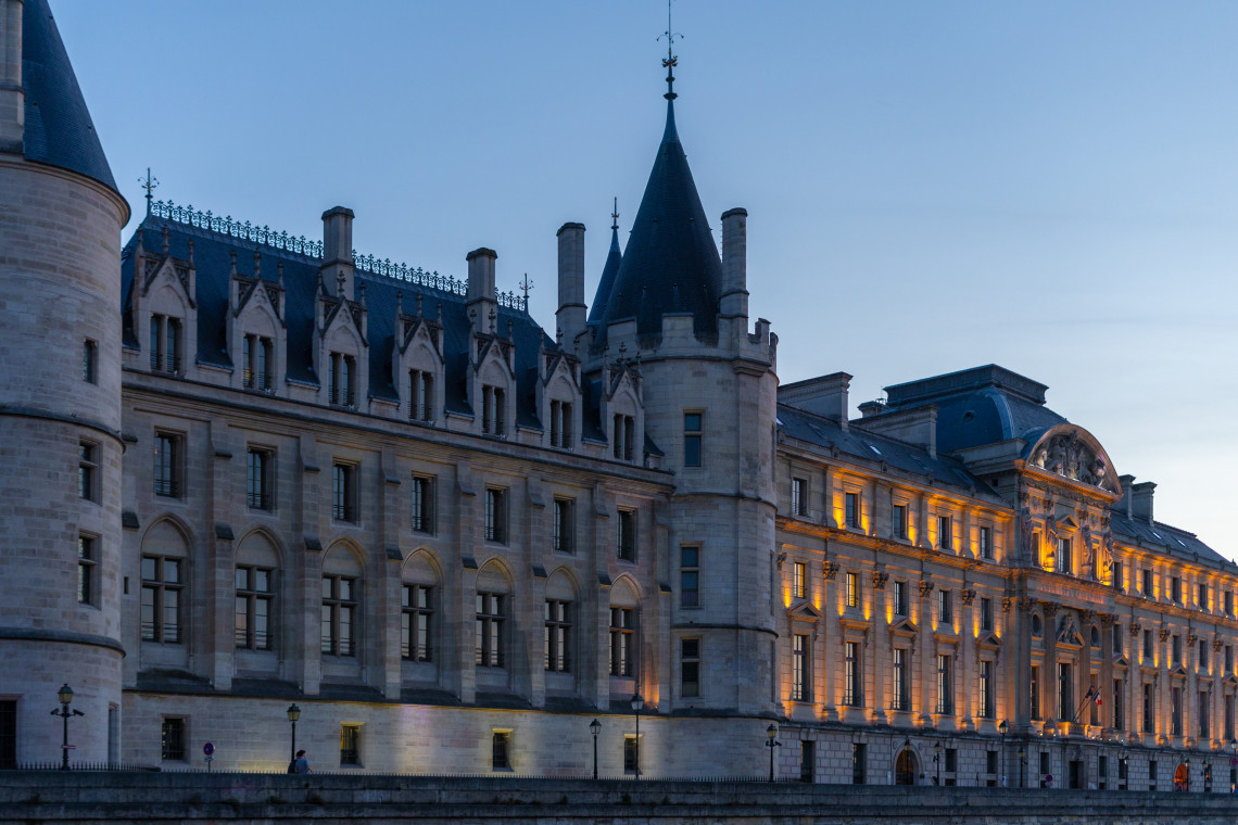  Illuminated Conciergerie medieval palace and prison on the Ile de la Cite along the Seine River at dusk, Paris, France
