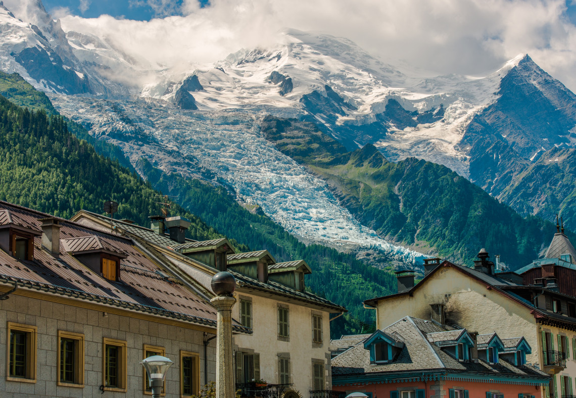 Chamonix town rooftops with Mont Blanc and the Bossons glacier descending through pine forests in the French Alps, France