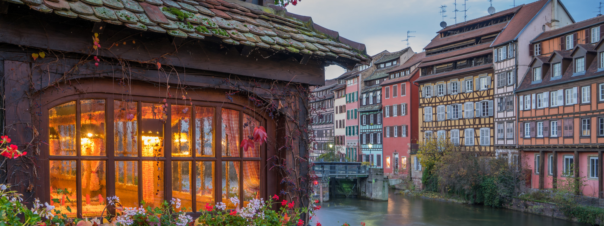 Traditional half-timbered houses and festive Christmas lights in La Petite France, Strasbourg, France. The historic canal district is decorated for the Strasbourg Christmas Market, creating a picturesque winter scene.
