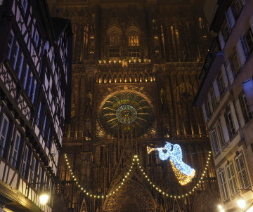 Night view of Strasbourg Cathedral during the Strasbourg Christmas Market in Strasbourg, France. Festive lights and holiday decorations illuminate the Gothic cathedral and surrounding historic streets.