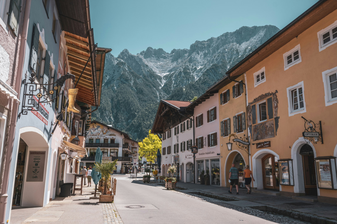 Traditional painted buildings line a street in Mittenwald, with the rugged Karwendel Mountains rising directly behind the Bavarian town.