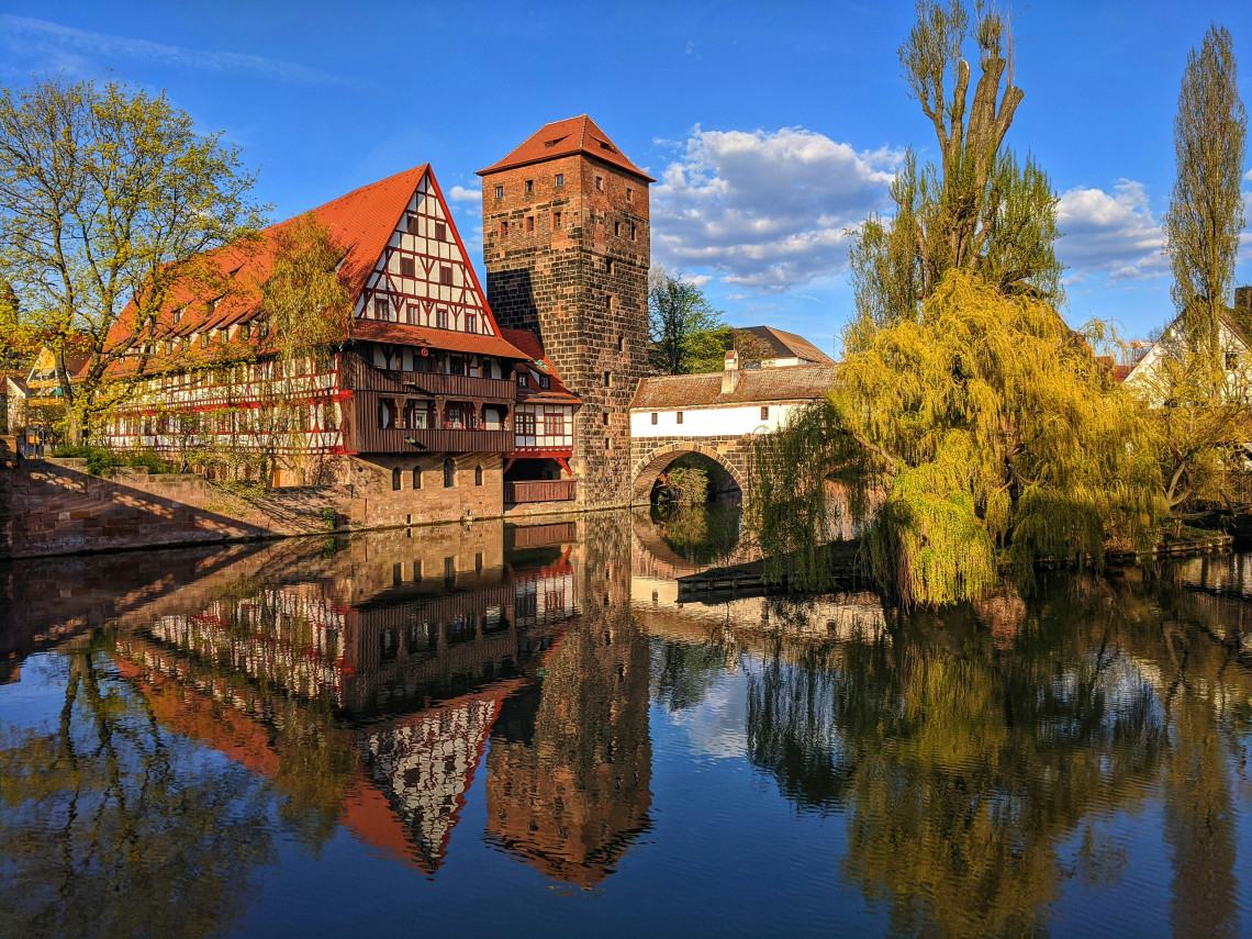 Historic half-timbered Weinstadel and medieval Water Tower reflected in the Pegnitz River in Nuremberg&rsquo;s old town.