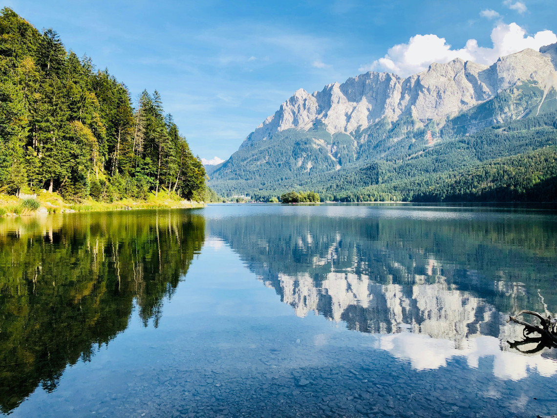 Clear waters of Hintersee mirror forested slopes and dramatic mountain peaks in the Bavarian Alps near Ramsau bei Berchtesgaden.