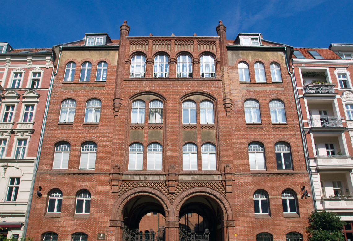 Symmetrical historic brick building in Berlin featuring tall arched windows, decorative masonry and twin entrance arches.