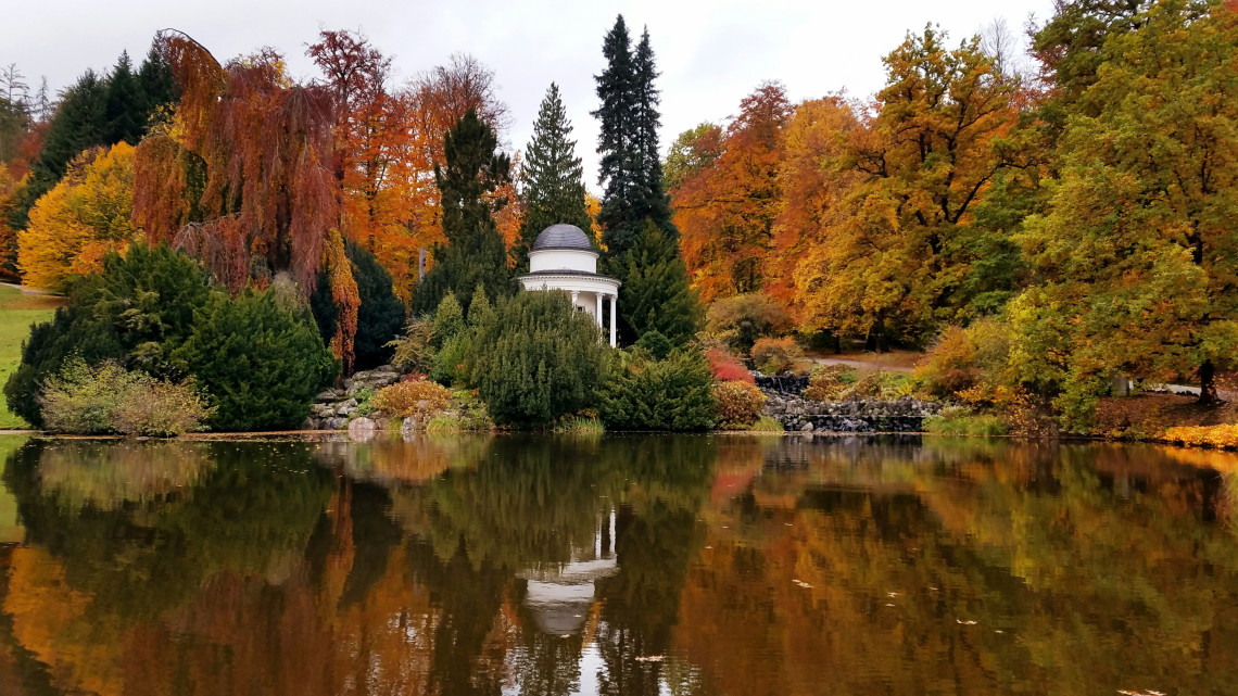 White domed Jussow Temple reflected in a calm pond surrounded by colorful autumn trees in Bergpark Wilhelmsh&ouml;he, Kassel.