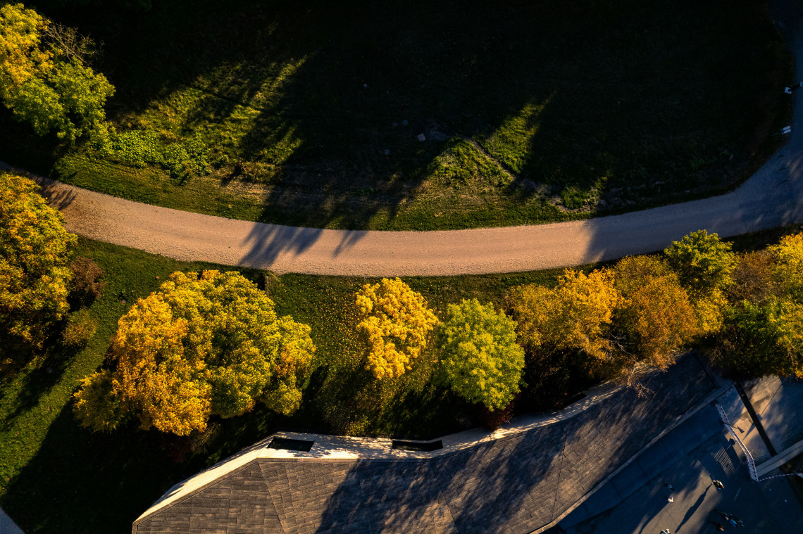Aerial view of a curved walking path bordered by golden autumn trees in Bergpark Wilhelmsh&ouml;he, Kassel.