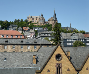 View across the historic rooftops of Marburg toward the hilltop Landgrave’s Castle and church towers in Hesse, Germany.