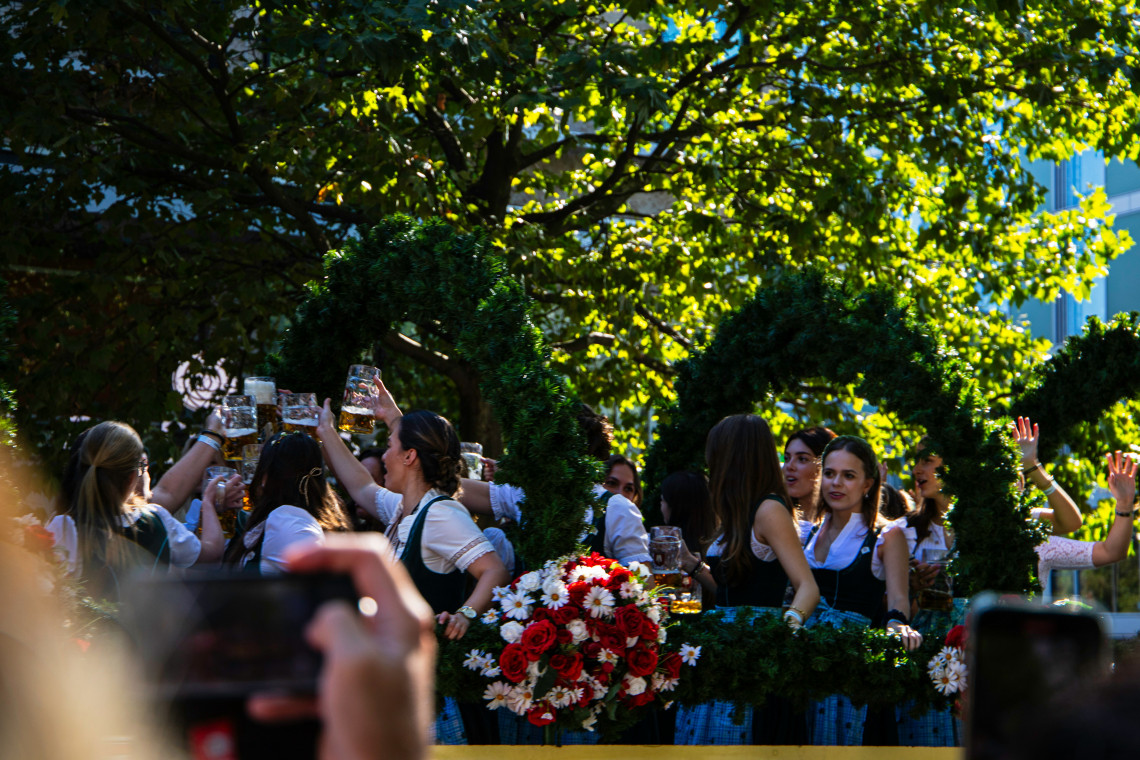 Women wearing traditional Bavarian dirndls raise beer steins during a festive Oktoberfest celebration in Munich.