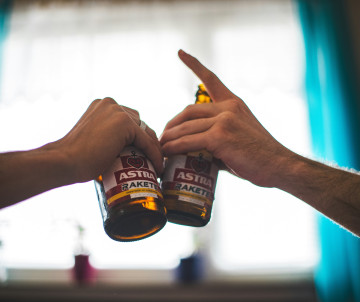 Two people clink bottles of Astra beer, a well-known beer brand associated with Hamburg, Germany.