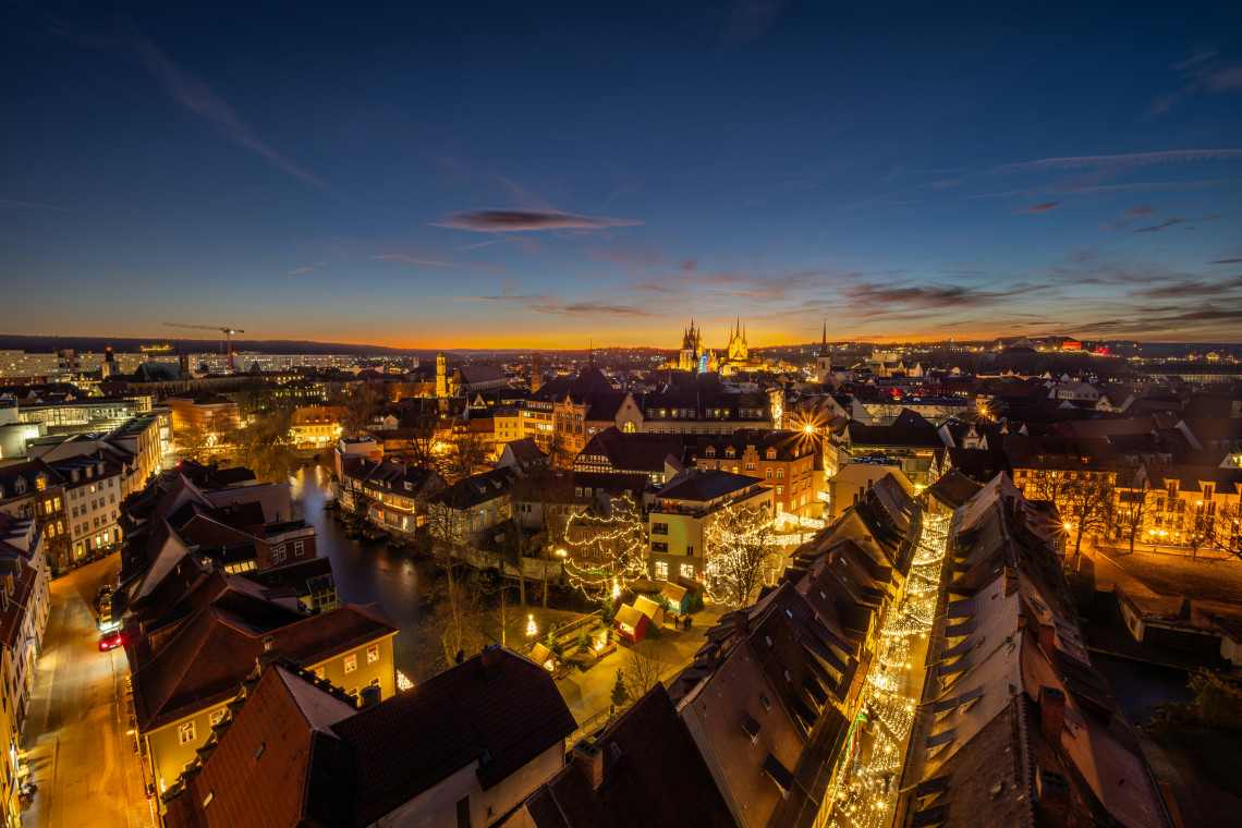 Christmas lights and market stalls illuminate the historic centre of Esslingen am Neckar, Germany. Church towers, canals and red-roofed buildings extend across the Old Town at sunset.