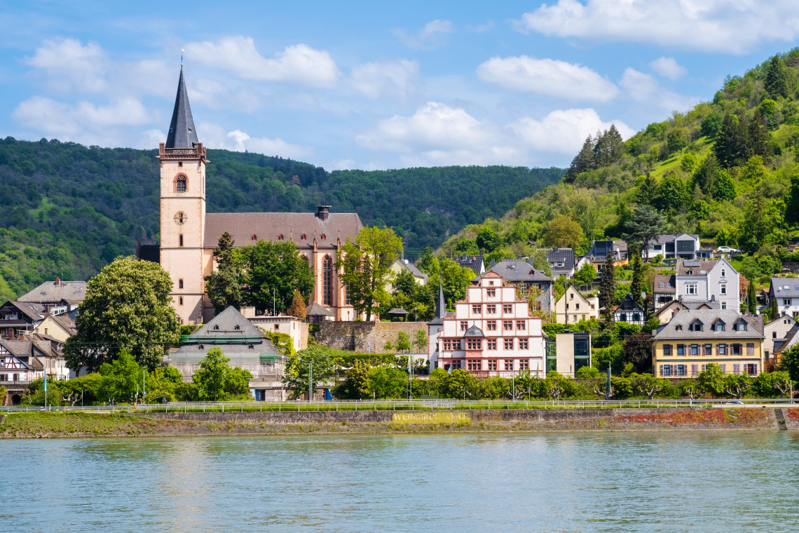 St Martin&rsquo;s Church rises above the riverside buildings of Lorch am Rhein, Germany. The historic town stands between the Rhine River and the forested hills of the Rheingau.