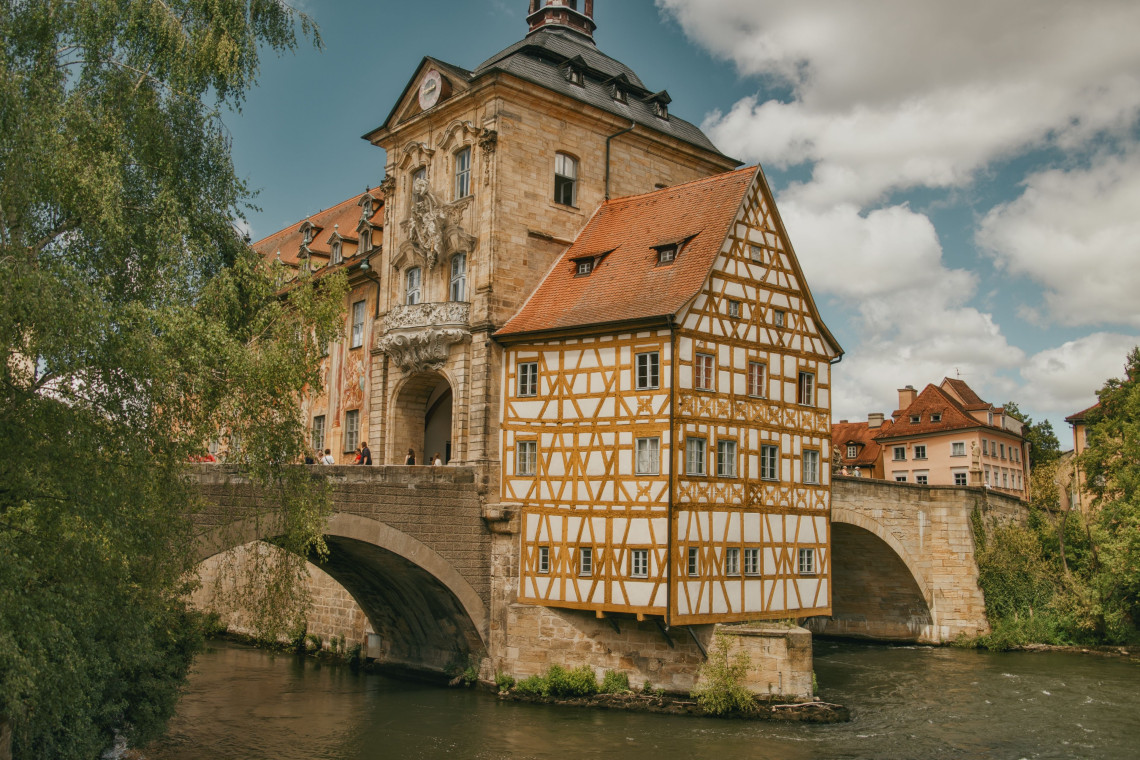Bamberg&rsquo;s Old Town Hall stands on a stone bridge above the Regnitz River in Bamberg, Germany. Its decorated Baroque fa&ccedil;ade and adjoining half-timbered section overlook the water.