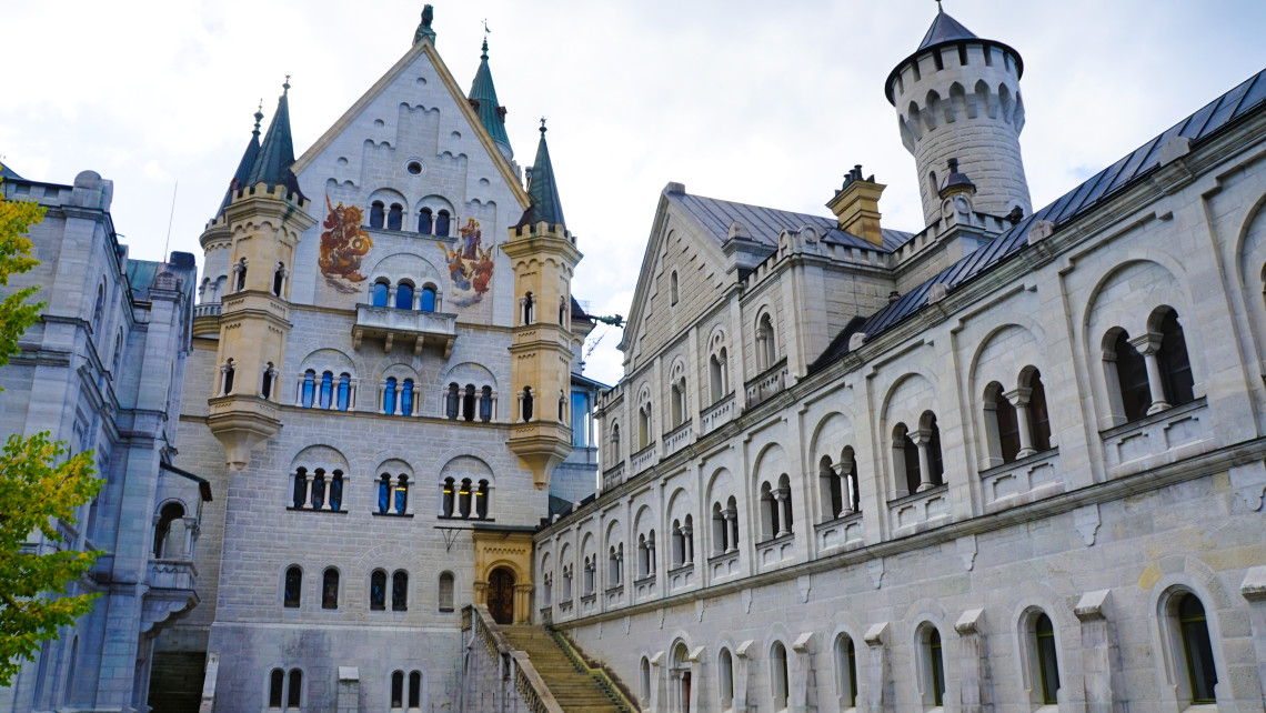 The inner courtyard of Neuschwanstein Castle near Schwangau, Germany, is enclosed by pale stone walls, arched windows, decorative towers and steep slate roofs.