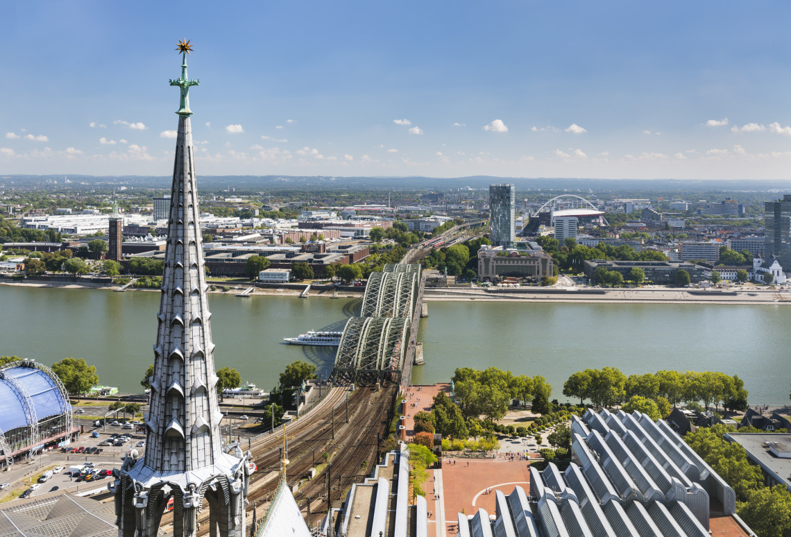 Elevated view across the Rhine River in Cologne, with the Hohenzollern Bridge connecting the city center and the Deutz district.