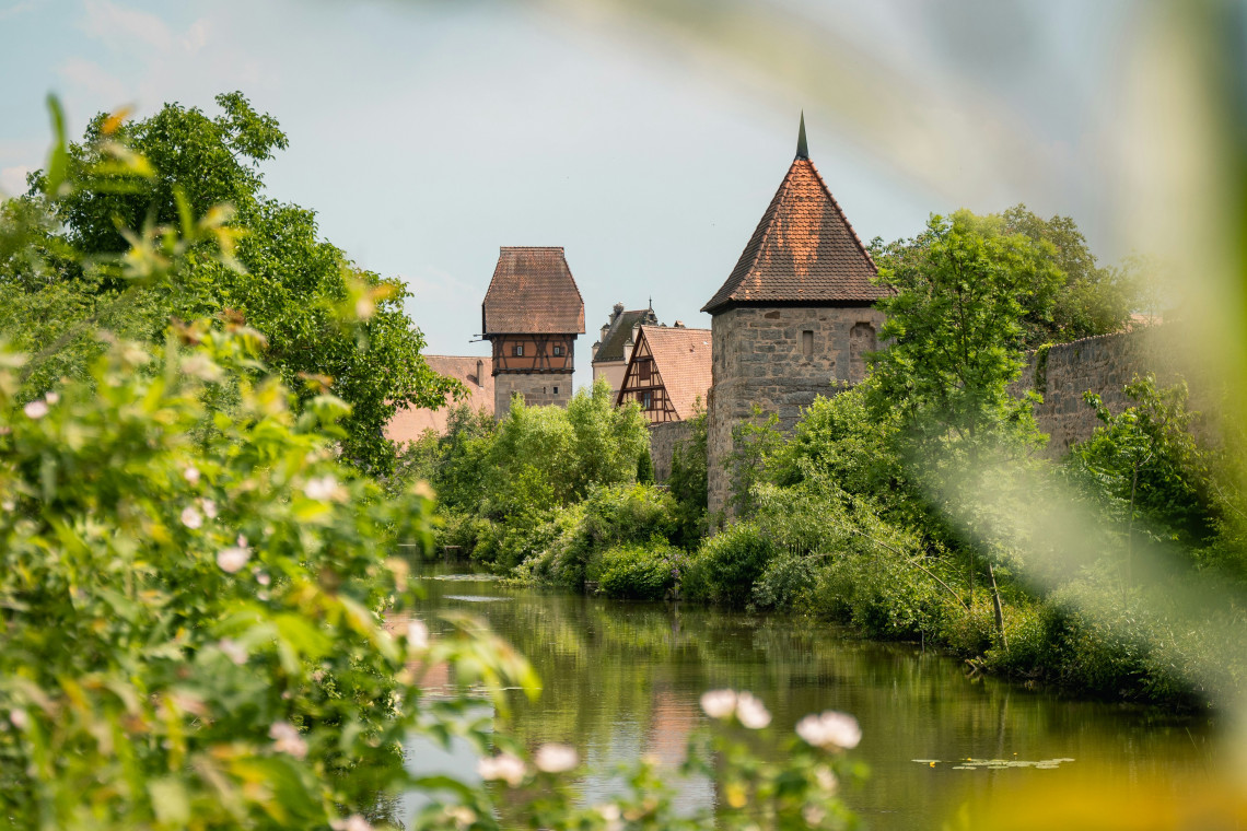 Medieval defensive towers and stone walls surrounded by greenery beside the historic old town of Dinkelsb&uuml;hl on Germany&rsquo;s Romantic Road.