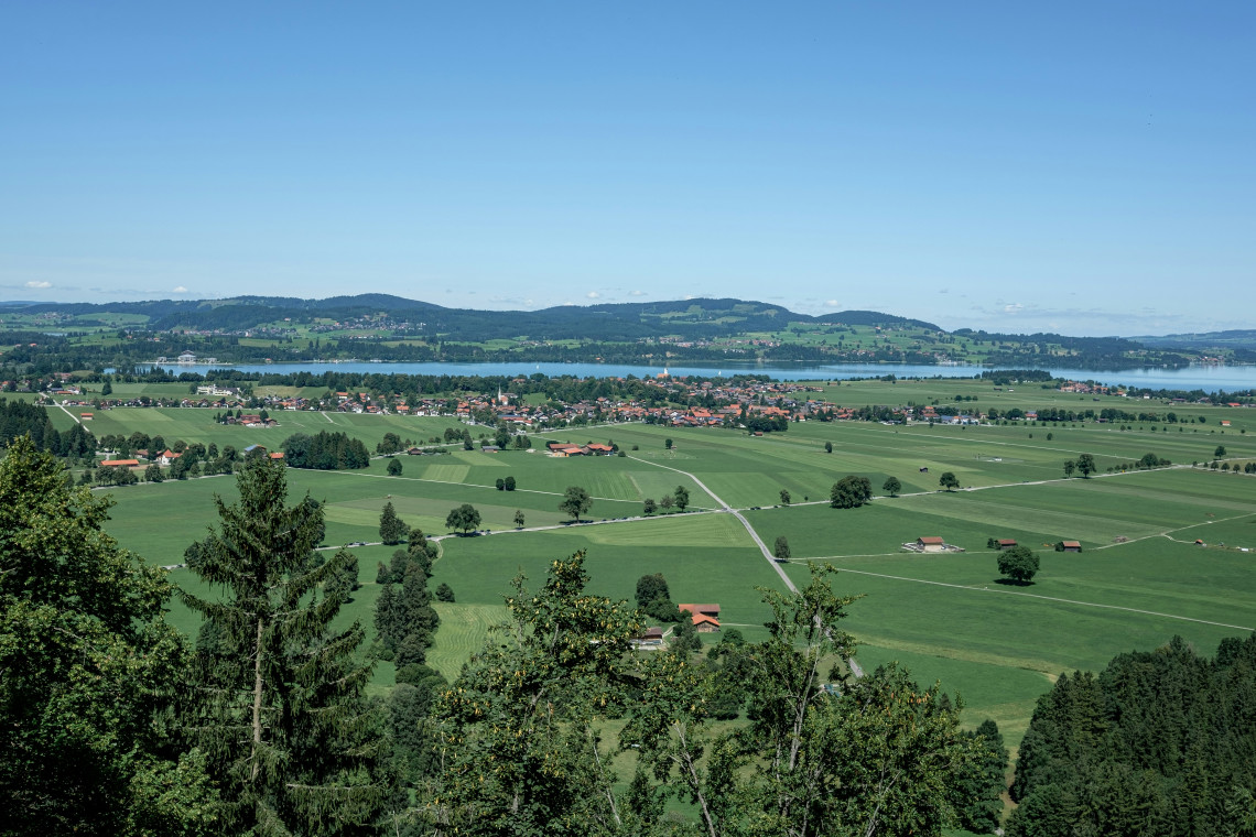 Panoramic view across green farmland and villages toward Forggensee near F&uuml;ssen in Bavaria, Germany.