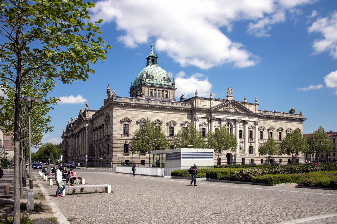 The Federal Administrative Court in Leipzig, Germany, features an ornate stone fa&ccedil;ade and a large copper-covered dome. A cobblestone plaza, trees and pedestrians fill the foreground.