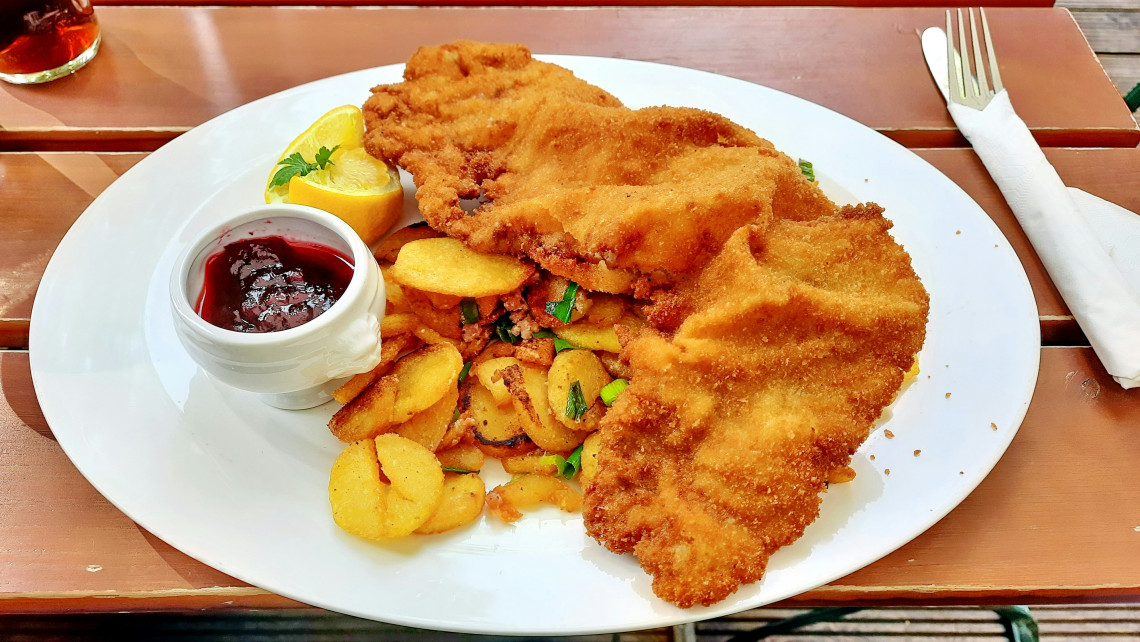 Traditional Wiener Schnitzel served in Vienna, Austria, with breaded veal cutlets, pan-fried potatoes, lemon and cranberry sauce on a white plate.