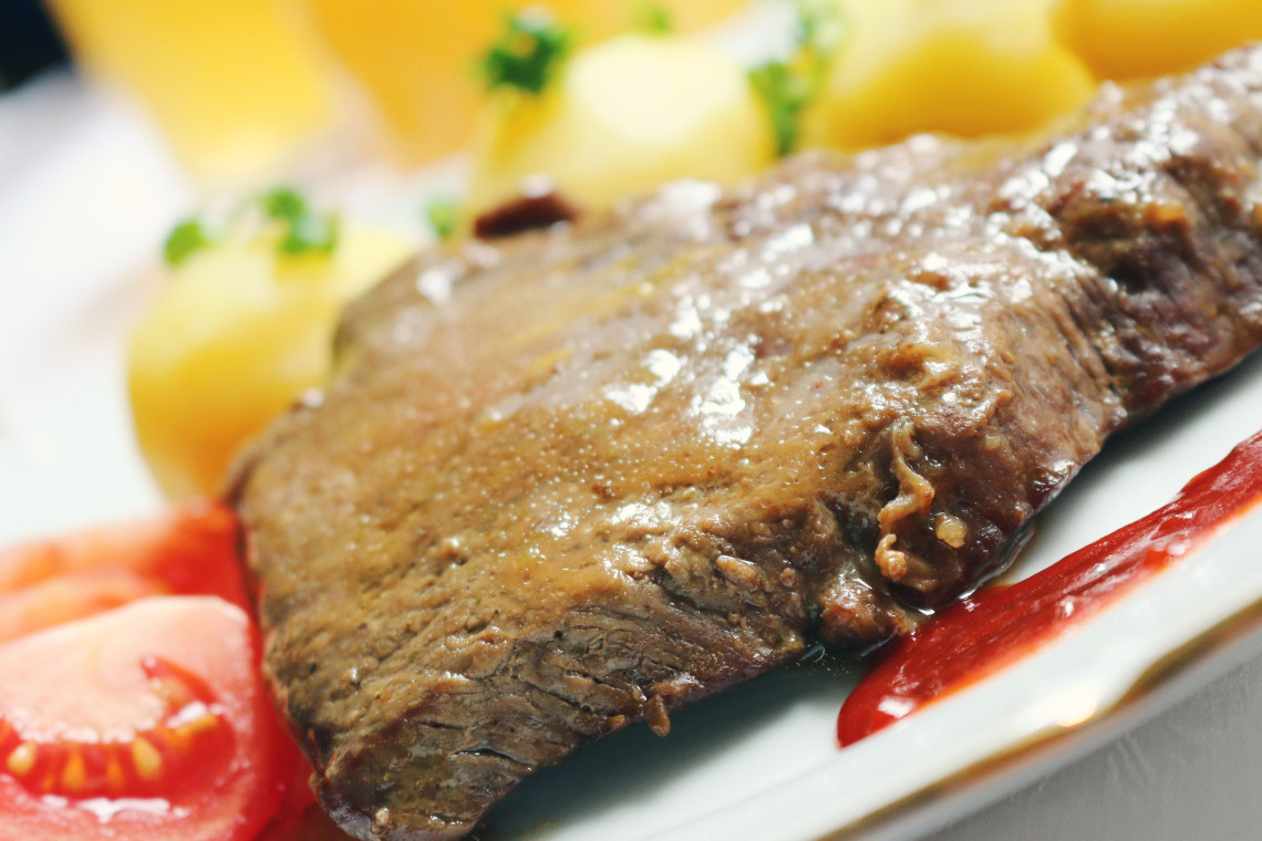 Traditional Tafelspitz served in Vienna, Austria, featuring tender boiled beef with potatoes, tomatoes and sauce. The dish is a long-established part of Viennese cuisine.
