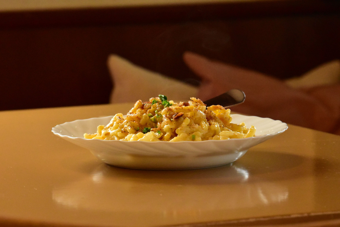 A plate of traditional Austrian K&auml;sesp&auml;tzle topped with melted cheese, herbs and fried onions. The Alpine comfort dish is commonly served in mountain restaurants across Austria.