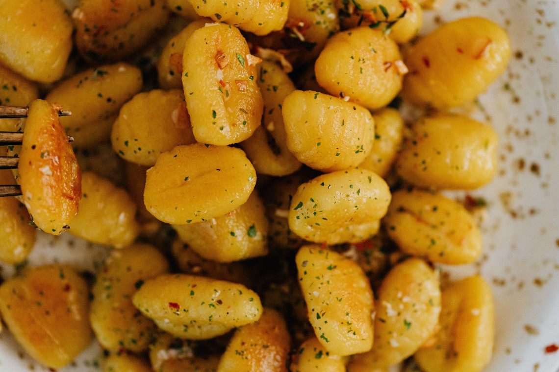 Close-up of Kasnocken served in Salzburg, Austria, with small golden dumplings coated in cheese, herbs and lightly browned onions. The regional dish is a Salzburg variation of Austrian cheese noodles.