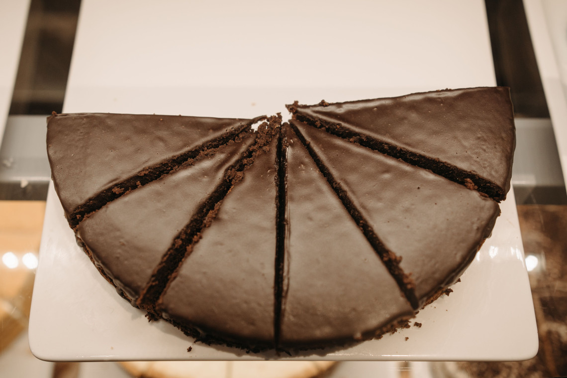 Slices of Sachertorte are arranged beneath a smooth dark chocolate glaze in Vienna, Austria. Thin layers of chocolate sponge and apricot filling are visible between each portion.