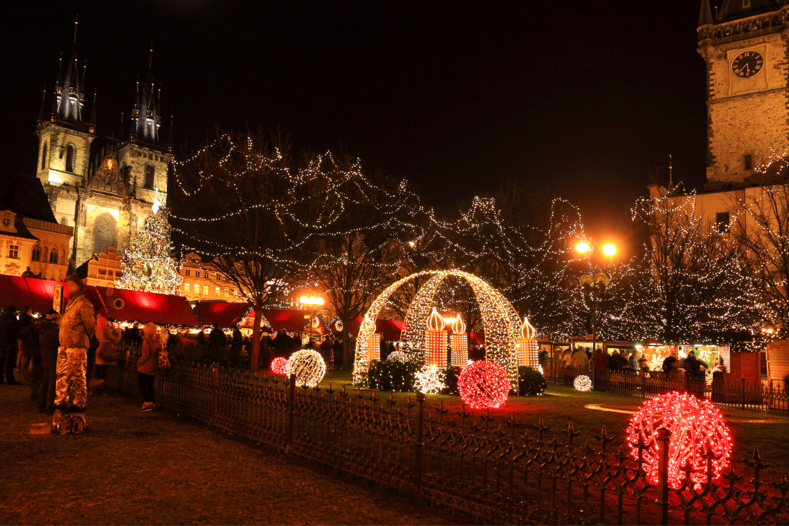 Christmas lights, market stalls and illuminated decorations fill Old Town Square in Prague, Czech Republic. The Church of Our Lady before T&yacute;n and the Old Town Hall tower rise behind the festive scene.