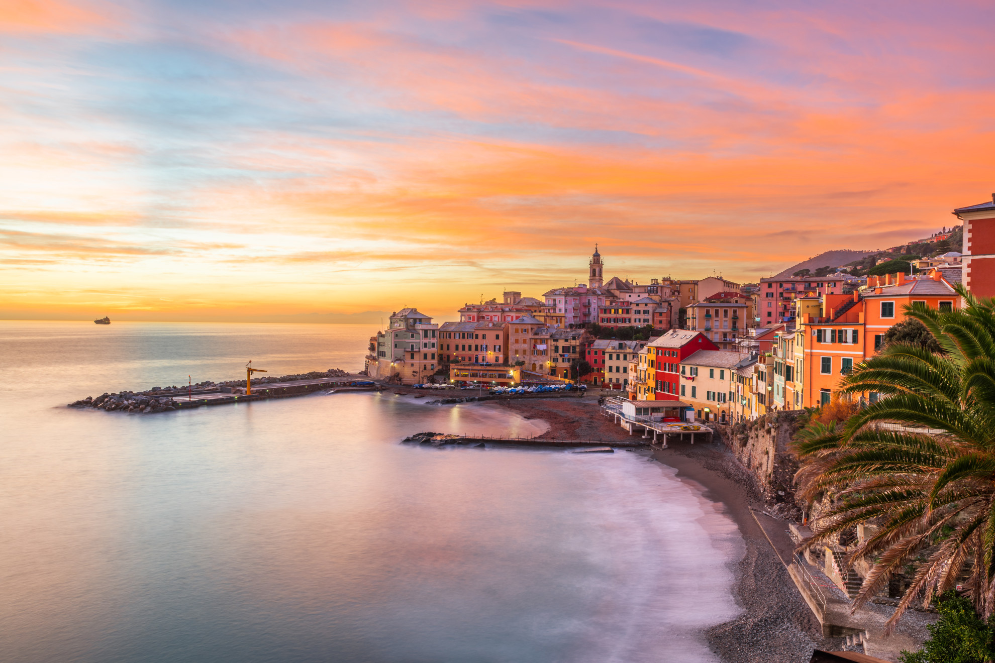 Colorful seafront buildings of Bogliasco at sunset with pastel sky reflected on calm water, Ligurian coast, Italy