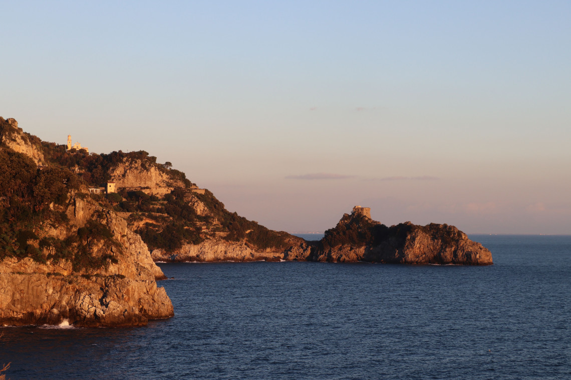 Rocky headlands surround Torre di Capo di Conca in Conca dei Marini on Italy&rsquo;s Amalfi Coast. Warm evening light falls across the rugged Mediterranean coastline and the historic stone watchtower.