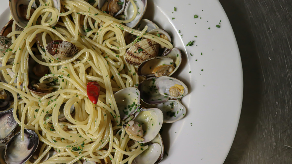 A plate of spaghetti alle vongole served with clams, parsley and a small piece of red chilli. The seafood pasta reflects the coastal cuisine associated with Campania and the Amalfi Coast in southern Italy.