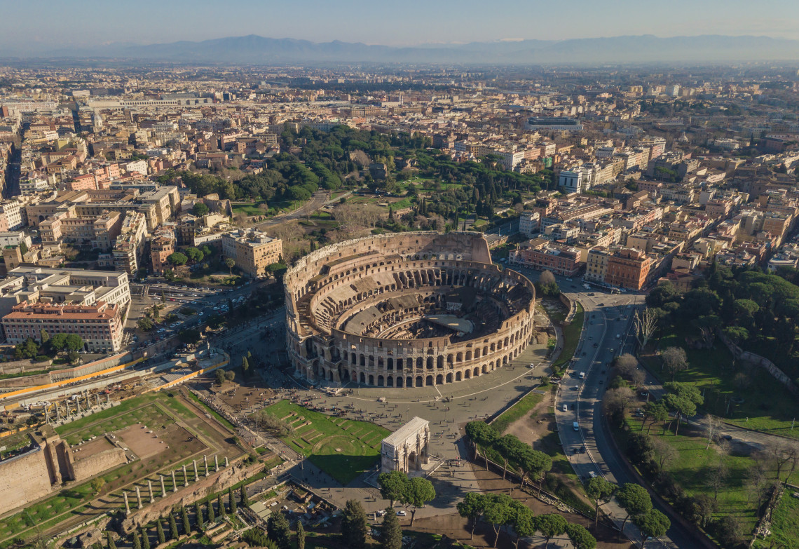 Aerial view of the Colosseum in central Rome, surrounded by the archaeological remains, streets and urban landscape of the Italian capital.