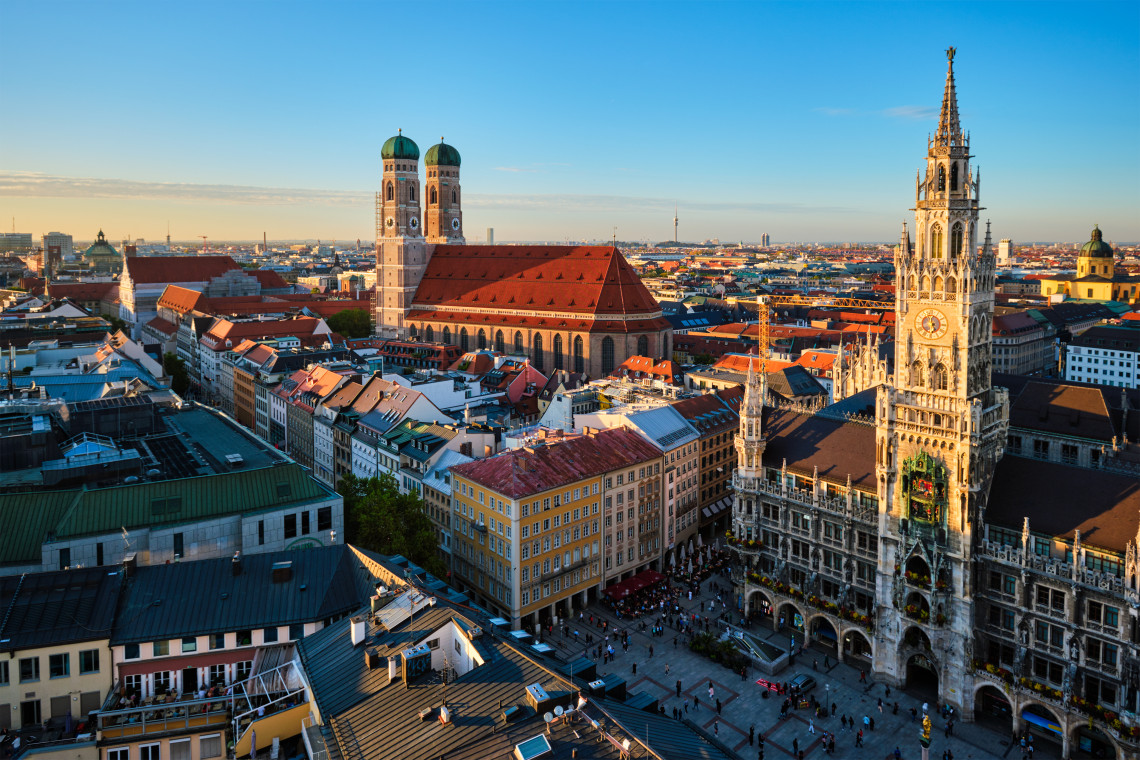 Elevated view of Marienplatz in central Munich, with the Gothic New Town Hall in the foreground and the twin towers of the Frauenkirche rising over the historic city center.